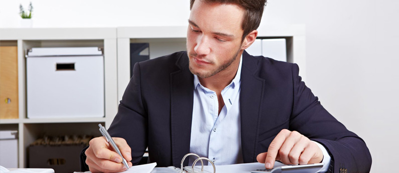 Professional Business Administrator working at his desk, writing in a binder.