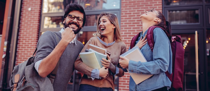 A male student and two females cheering on campus