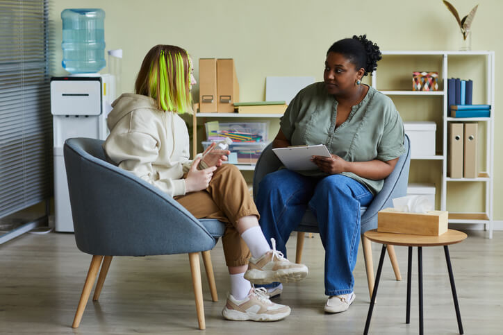 A social worker talking with a teenage girl in an office after community support worker training