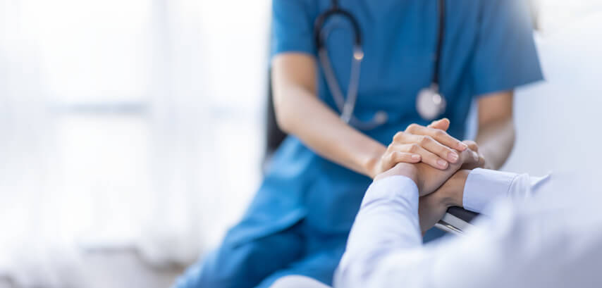 A nurse holding the hands of a patient after practical nurse training