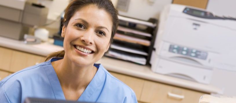 Dental Receptionist sitting at a desk in an office environment.