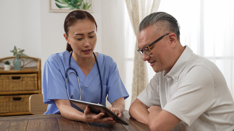 A healthcare assistant training grad showing a client information on a tablet