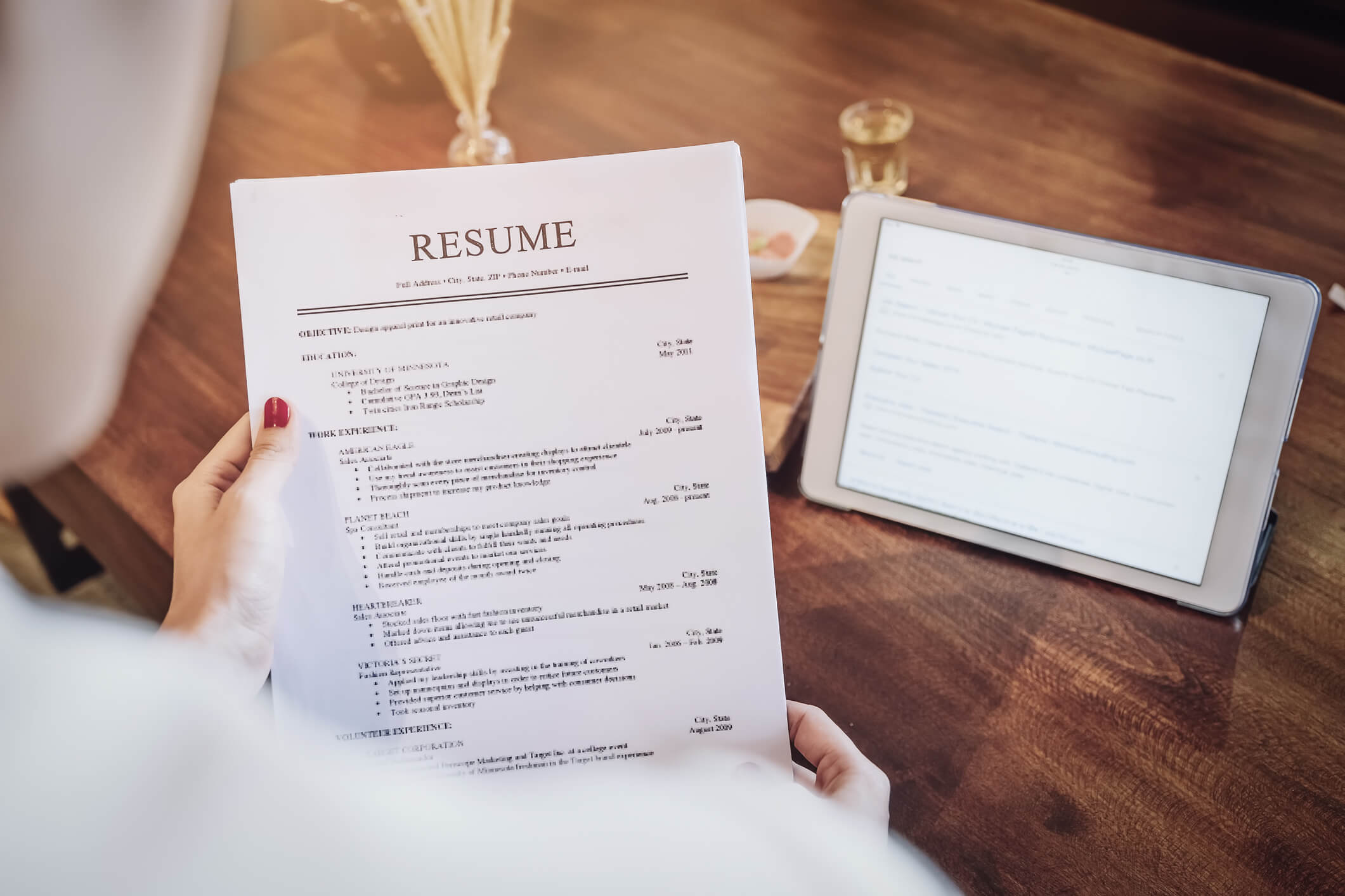 A smiling female healthcare assistant holding up her resume after completing her healthcare assistant training