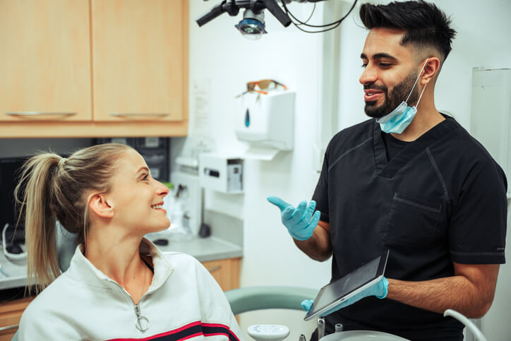 A dental assistant training grad educating a patient with a tablet