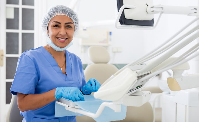 A dental assistant training grad preparing equipment in a clinic