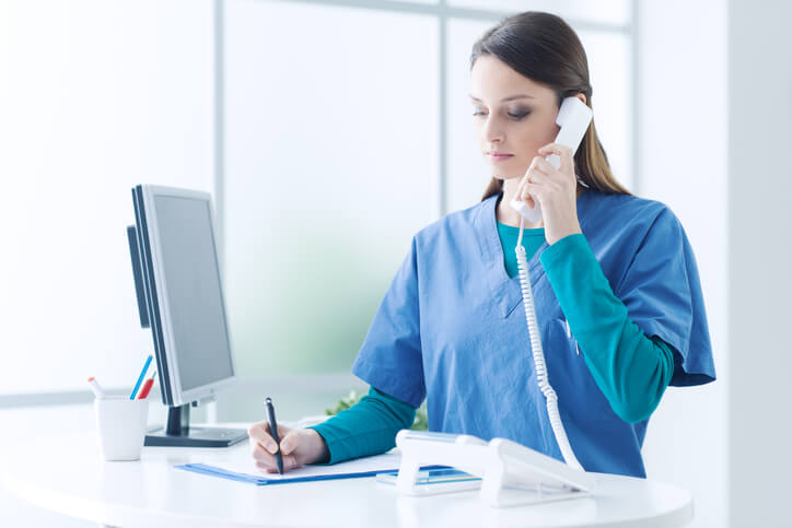 A female medical office administrator talking over the phone with a client after completing her medical office administration training