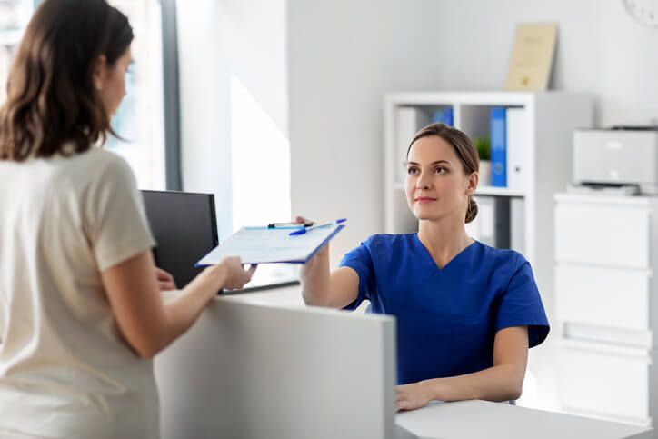 A female medical office assistant at the receptionist desk in a clinic after completing her medical office assistant training