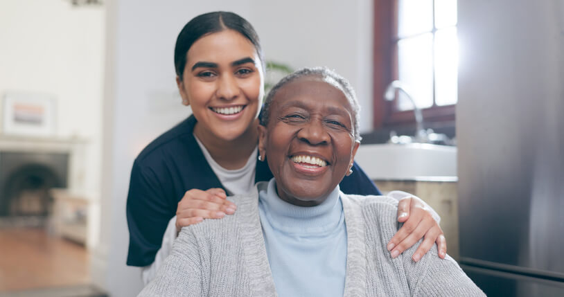 A smiling female community support worker with a female patient in a wheelchair