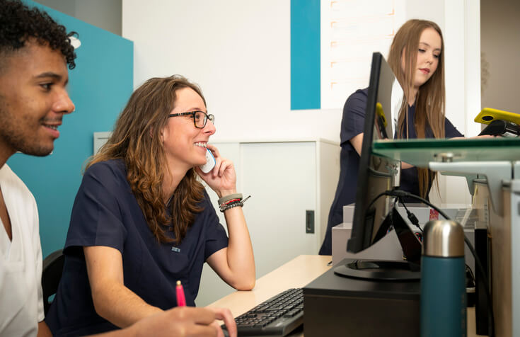 A medical office management training grad collaborating with colleagues in an office