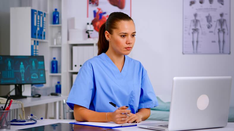 A focused female medical office assistant using medical billing software in an office after completing her dental office management training