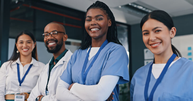 A team of healthcare assistant training grads posing together at a clinic