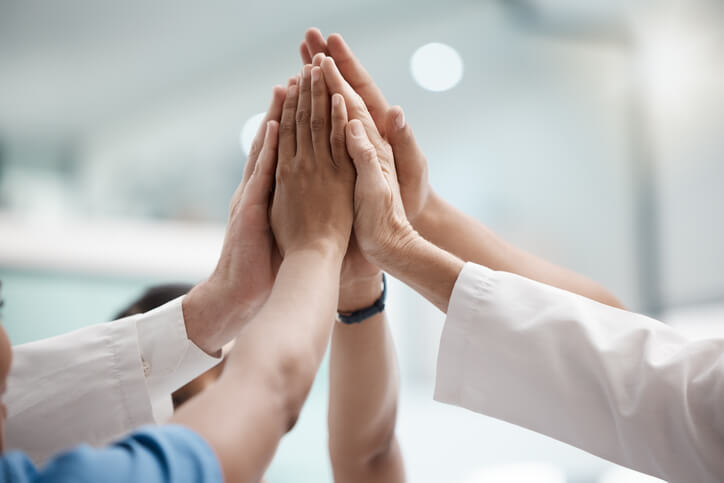 A team of healthcare assistant training grads doing a team high-five