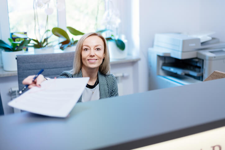 A friendly female records administrator at the reception office after completing her medical office administrator training