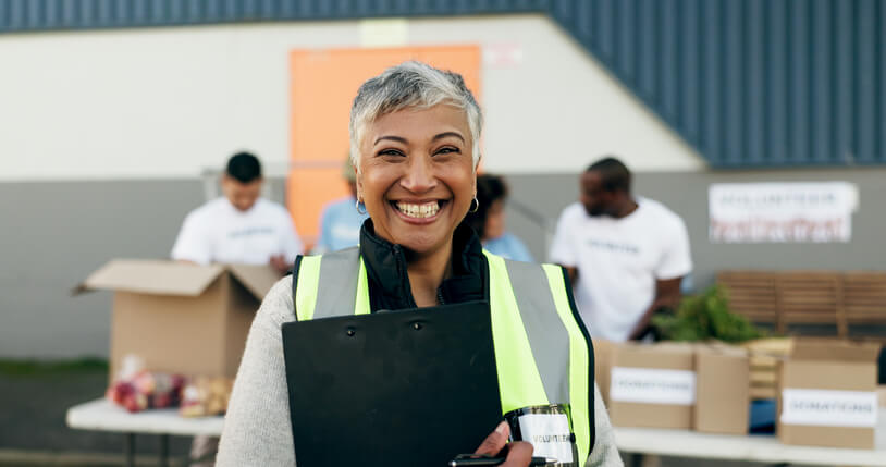 A smiling female community development worker at a community feeding event after her career training