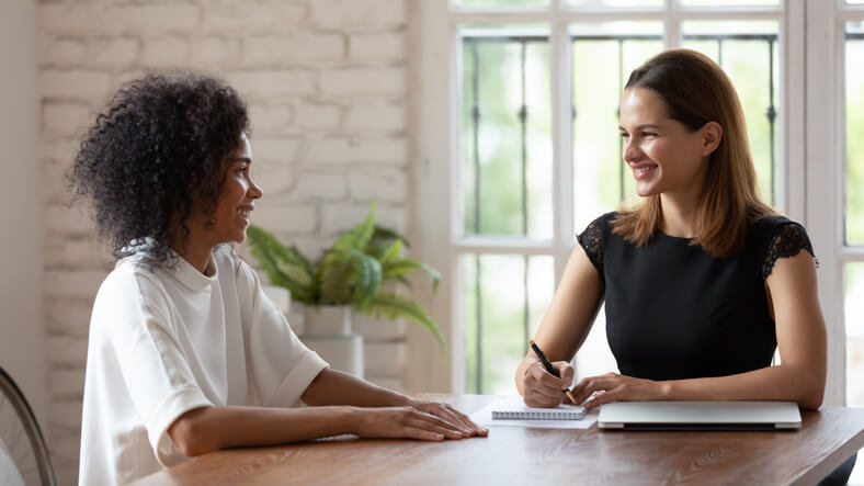 A friendly community support worker talking with a child at home after completing her community support worker training