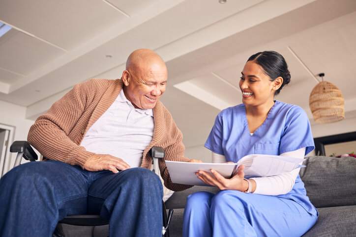 A healthcare training grad showing an elderly patient information on a tablet