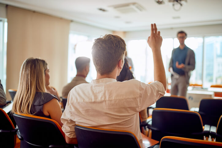 A career college student raising his hand in class