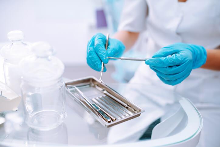 A dental assistant diploma graduate preparing tools before a patient appointment
