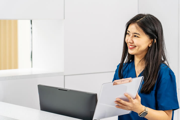 A medical office manager reviewing patient records at a front desk