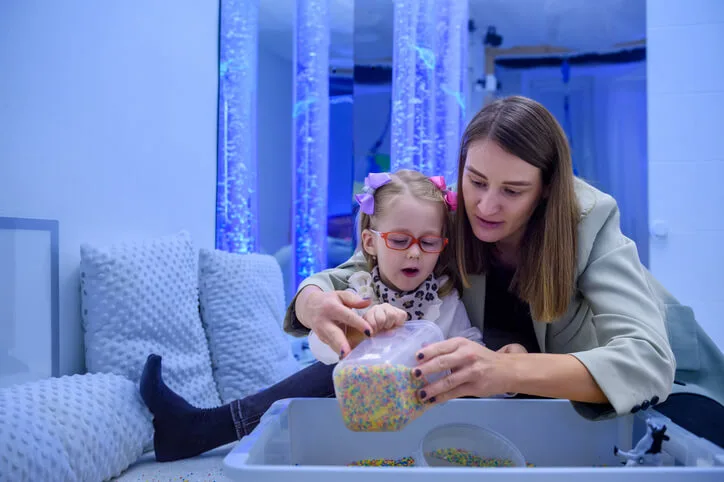 An Education Assistant training graduate supporting a child with sensory activities