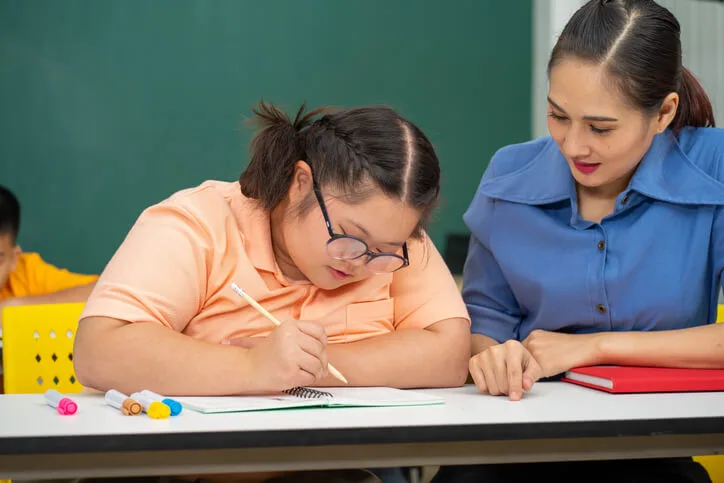 An education Assistant Training graduate helping a neurodiverse student during class