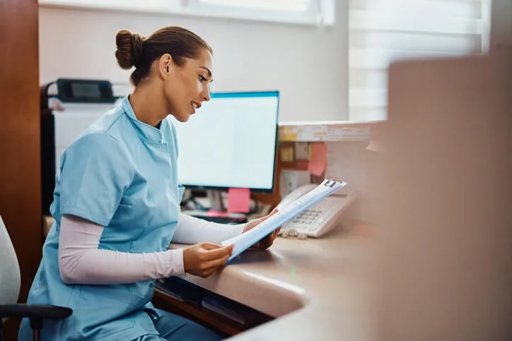 A dental assistant training graduate reviewing patient records in an office