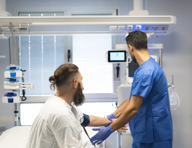 Licensed practical nurse checking vital signs in a patient room.