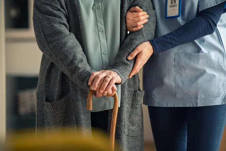 A health care assistant supporting an elderly patient in long-term care