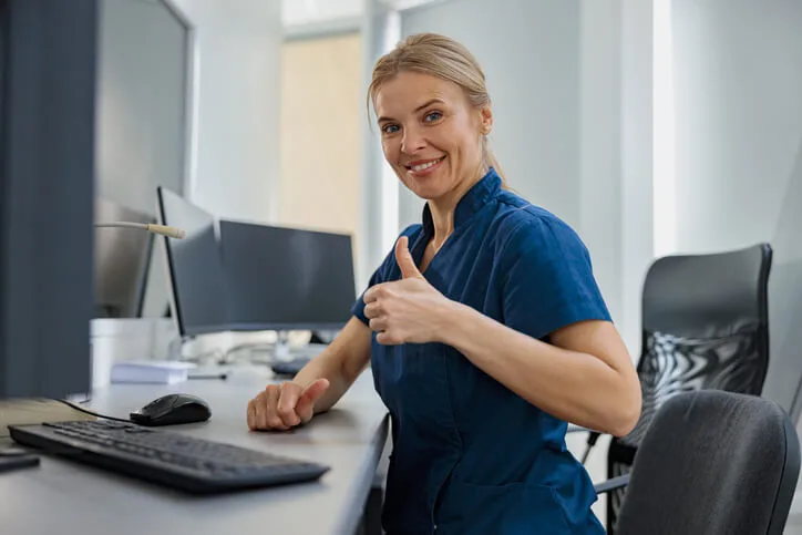 A dental office receptionist manages appointments and patient records using scheduling software in a busy clinic environment.