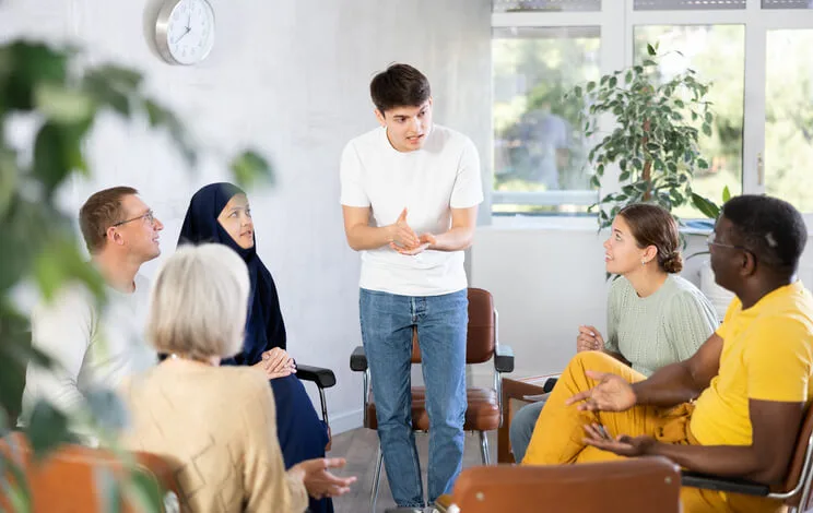 A support worker assisting individuals in a structured group program environment