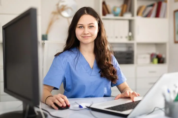 A dental reception student completes online training while learning appointment scheduling software.